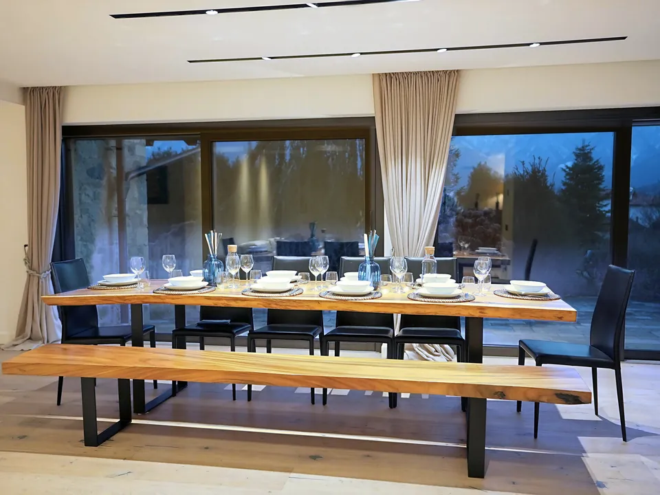 Dining area with a long laid wooden table and large glass doors