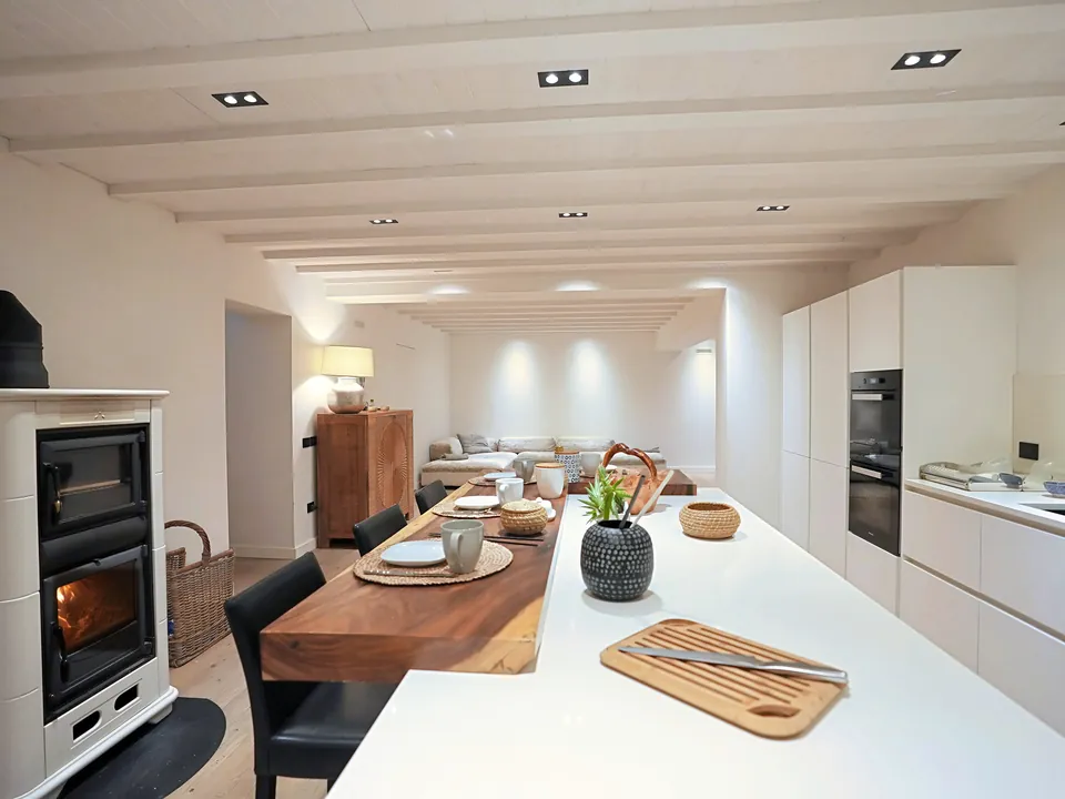 Kitchen with a lit wood-burning stove, wooden table and carved sideboard