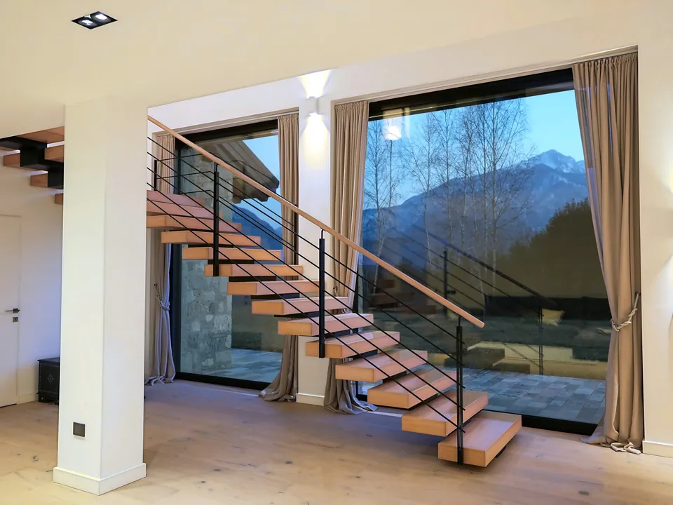 Floating wooden staircase and glazing with a view of the mountain at dusk