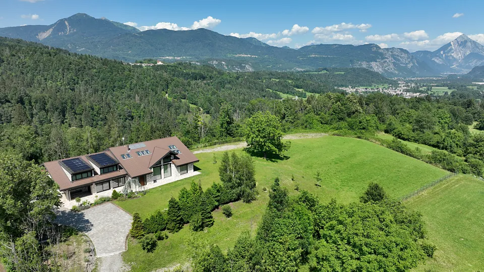 The house and the meadow from above, with the valley and a peak behind